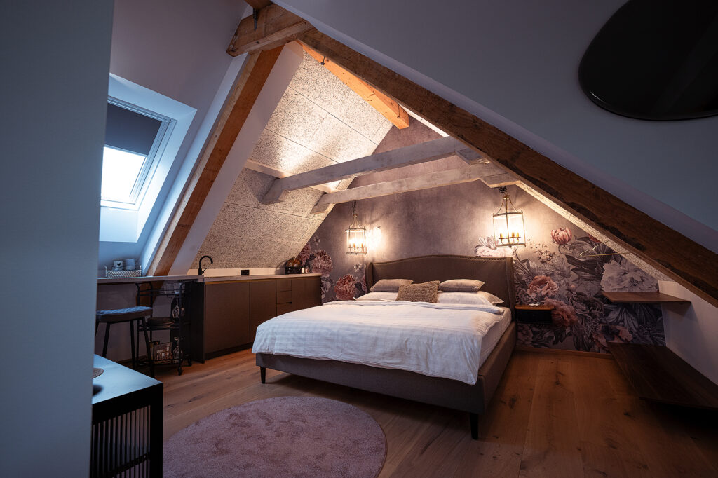 Schlafzimmer unter der Dachschräge mit Blumentapete in der Wohnung Steiermark